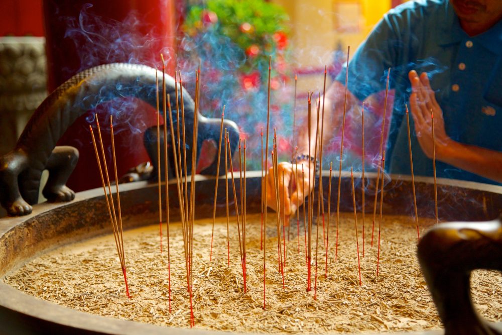 View of a man lighting incense sticks in Chinatown