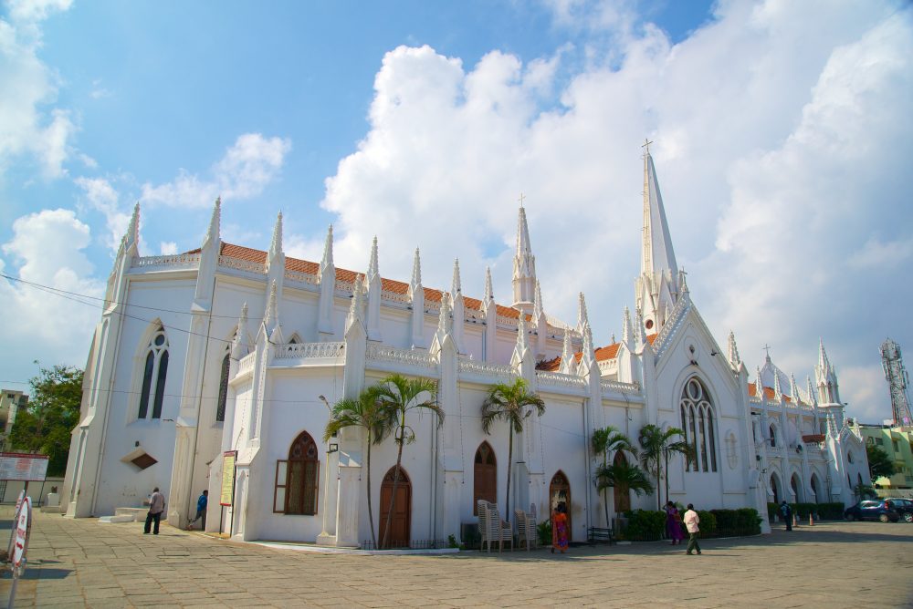 The San Thome cathedral, a white cathedral built in the Neo-Gothic style, with many spires and Gothic windows stands amid a stone plaza in Chennai